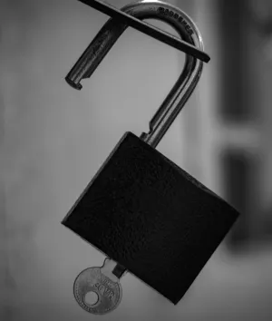 Open lock hanging on metal bar.